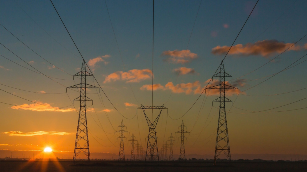 Torres de transmissão de energia elétrica ao pôr do sol, representando a infraestrutura do setor elétrico e a gestão de ETR.