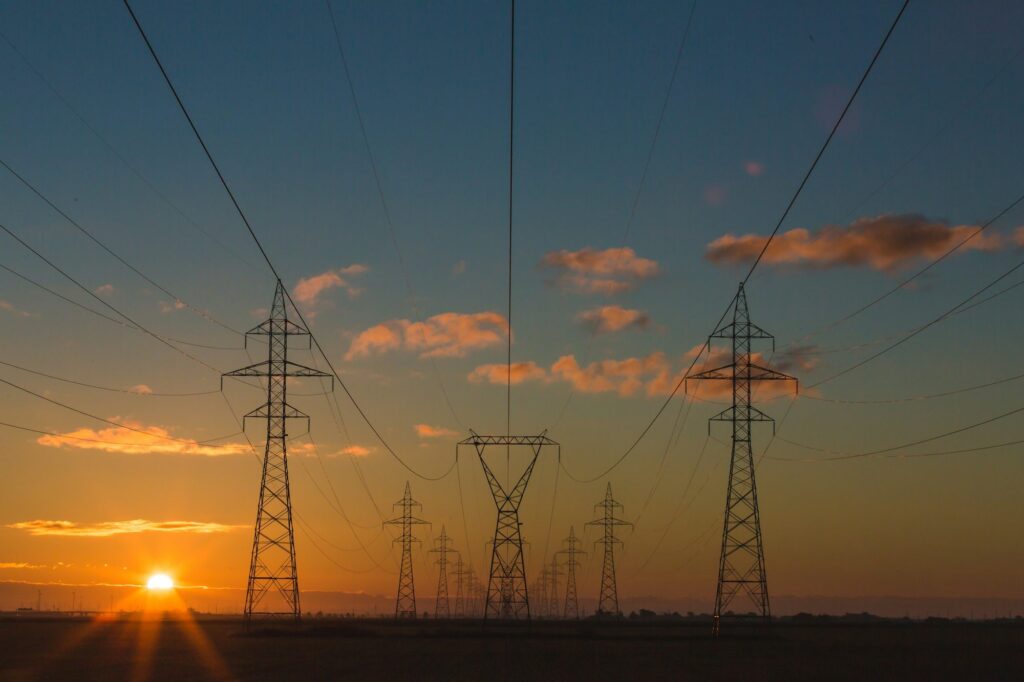 Torres de transmissão de energia elétrica ao pôr do sol, representando a infraestrutura do setor elétrico e a gestão de ETR.